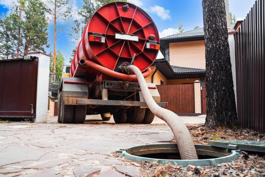 Abwassertankwagen. Kanalisationspumpmaschine. Klärwerk-LKW. Rohr in der Entwässerungsgrube. Abpumpen von Abwasser aus einer Klärgrube. Klärgrube Service