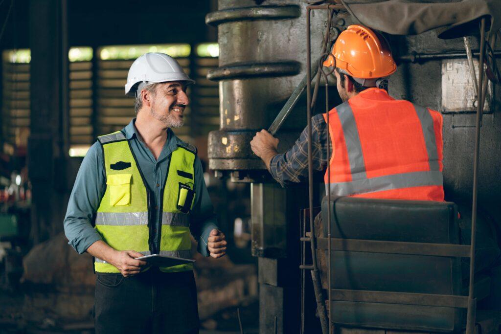 Professioneller Techniker-Ingenieur mit Schutzhelm, der an der Wartung von Baumaschinen in Industriefabriken arbeitet, Inspektionsmann mit Produktionsberuf in der Produktionstechnik